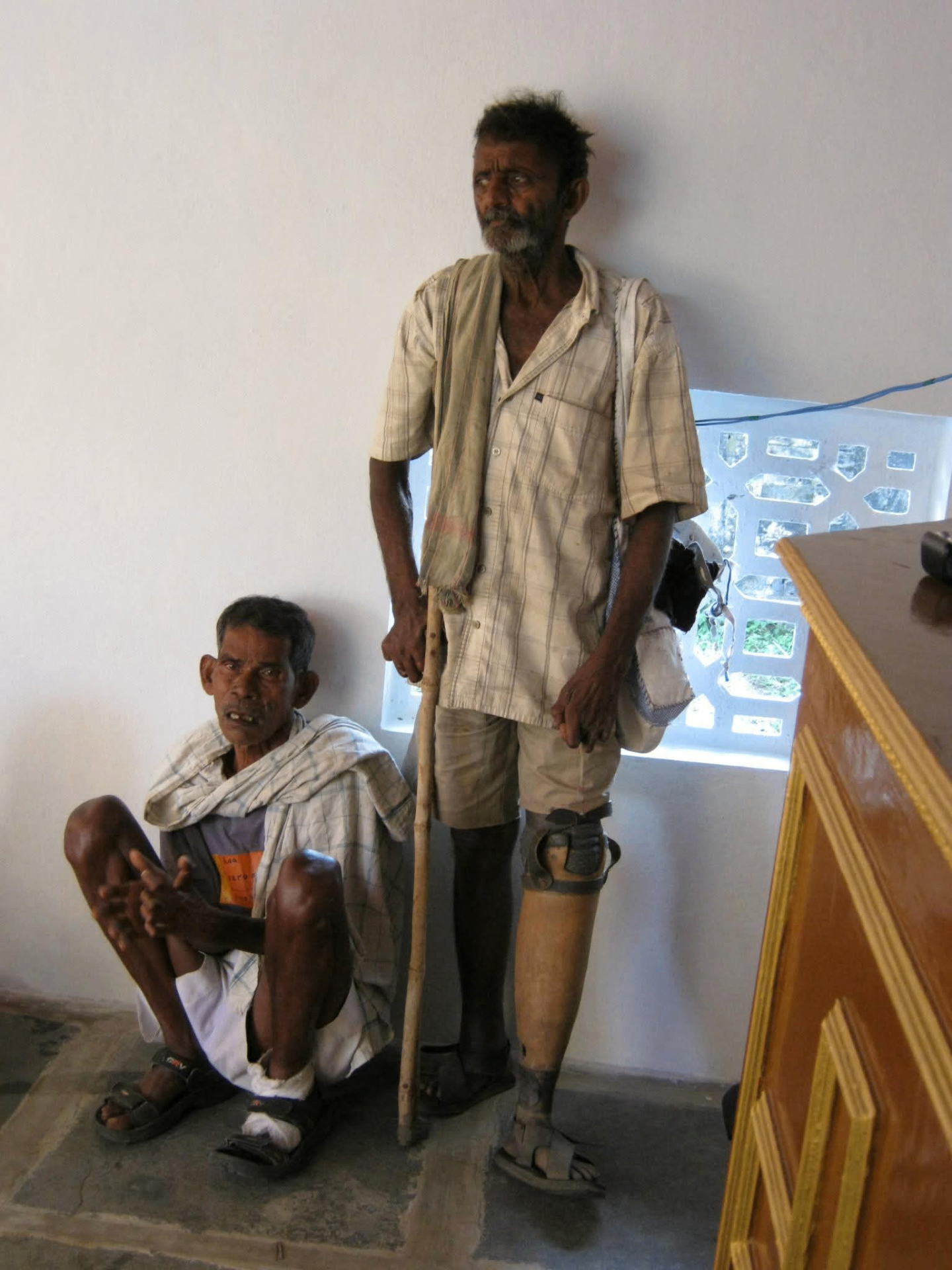 Two leprosy patients with walking aids inside the ministry hall