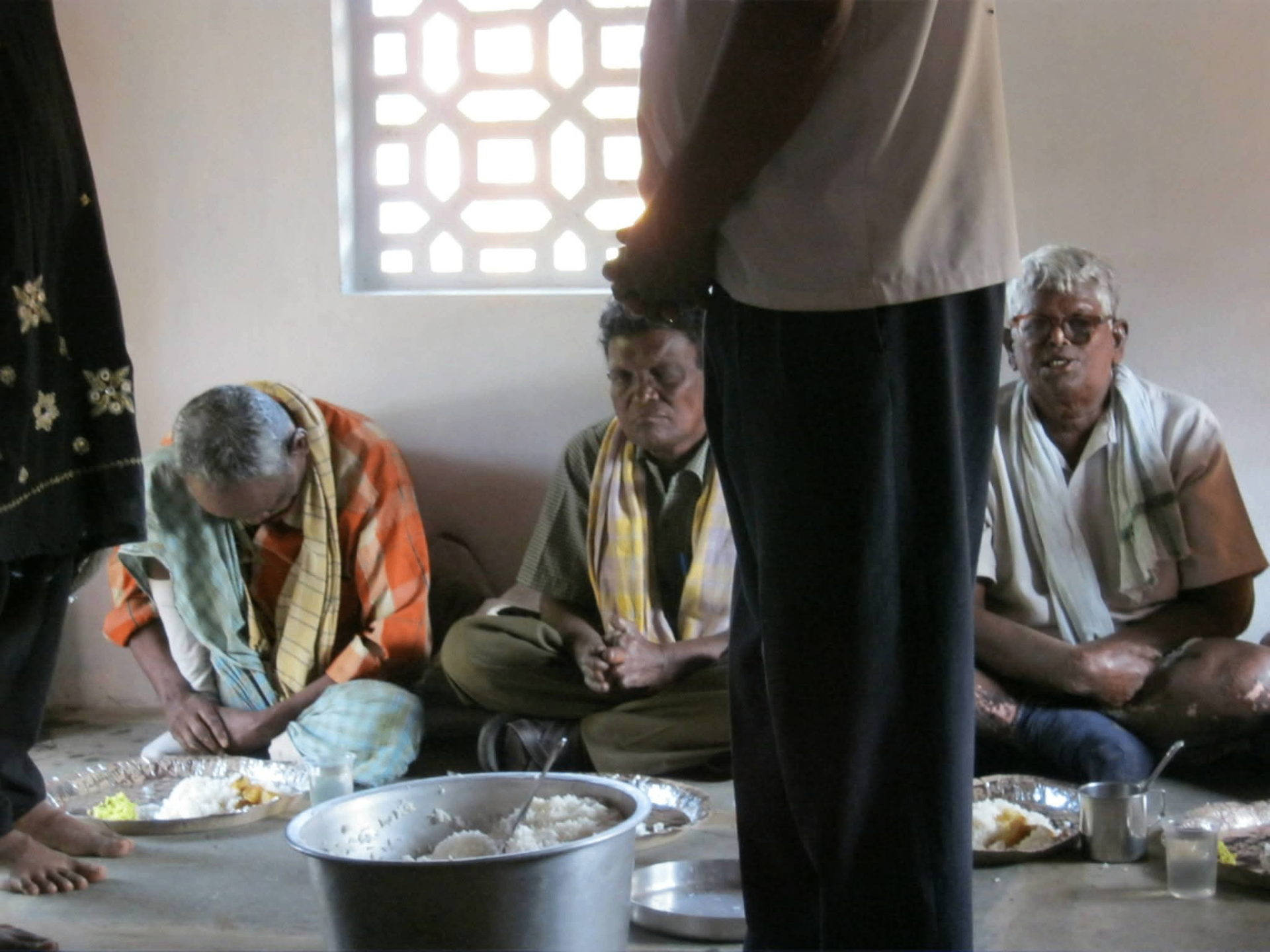 Pastor praying over leprosy patients during meal fellowship