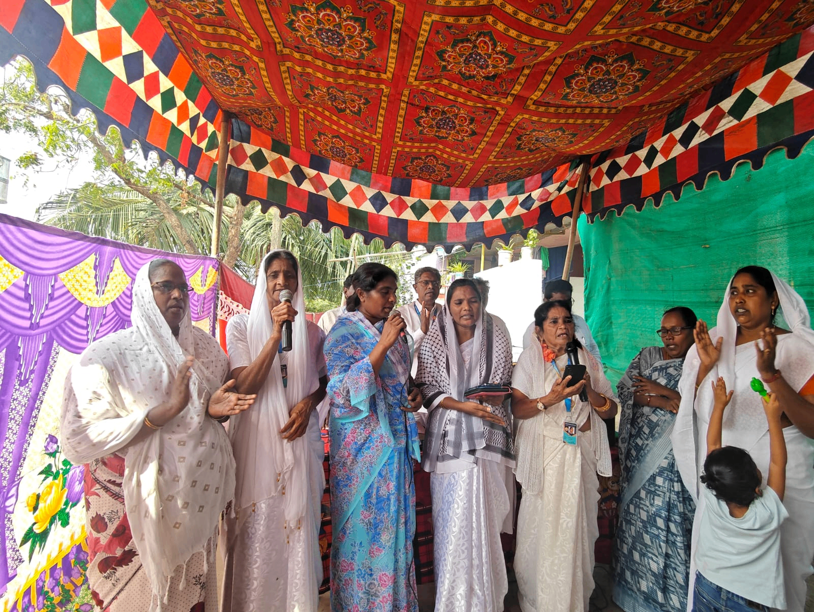 Women singing and worshipping together under a prayer tent